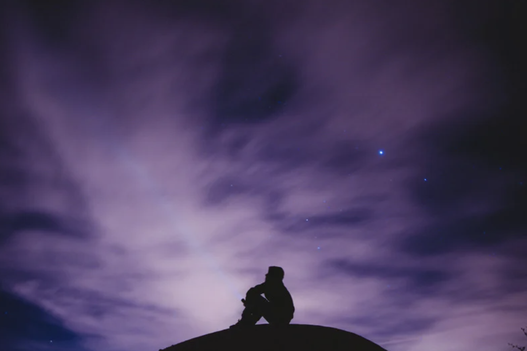 Man sitting looking up at the night sky